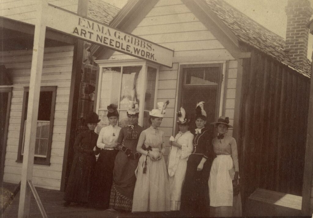 Emma G. Gibbs, center in white hat, in front of her milliner shop. Left: Annie Martin, Flora Pinniger, Mrs. Pinniger, Miss Gibbs, Mrs. Knowles, Etta Smith, and Frances Frey, 1900. Photo courtesy of the Nevada Historical Society.